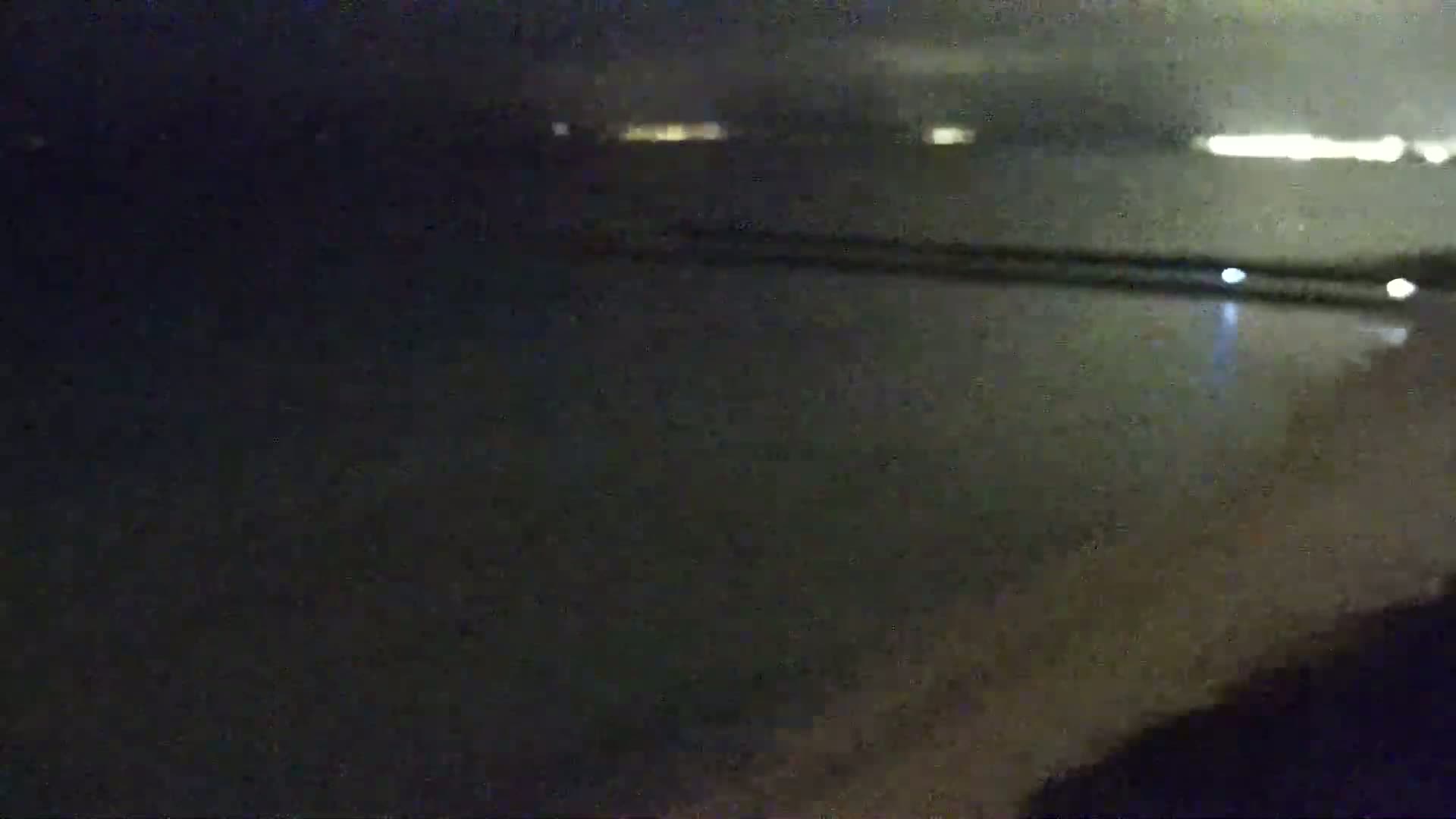 A dark, nighttime view of a body of water with distant lights visible across it.