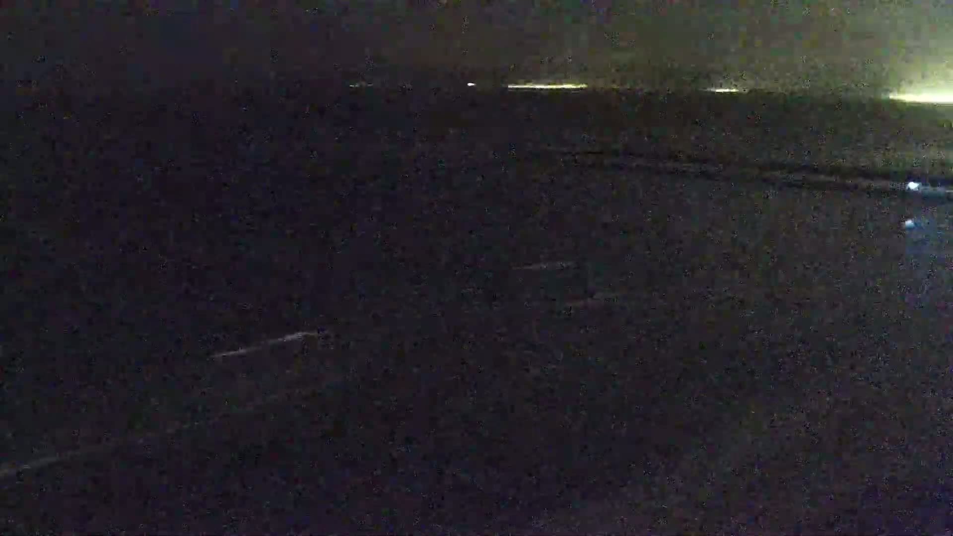A dark, nighttime view shows a blurry, possibly water-covered surface with faint lights in the distance.