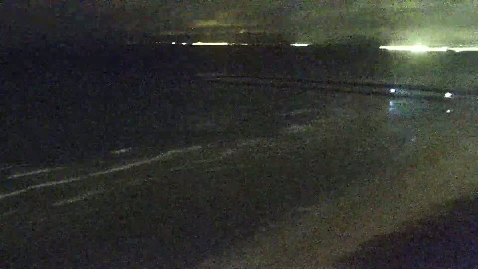 A dark, nighttime view of a body of water with faint waves visible under a mostly clear sky.