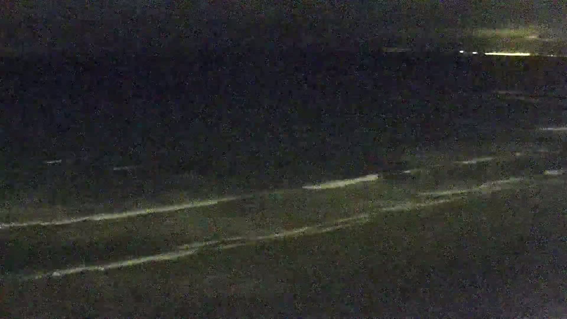 A dark, nighttime beach scene shows gently lapping waves on the shore under a mostly clear sky.