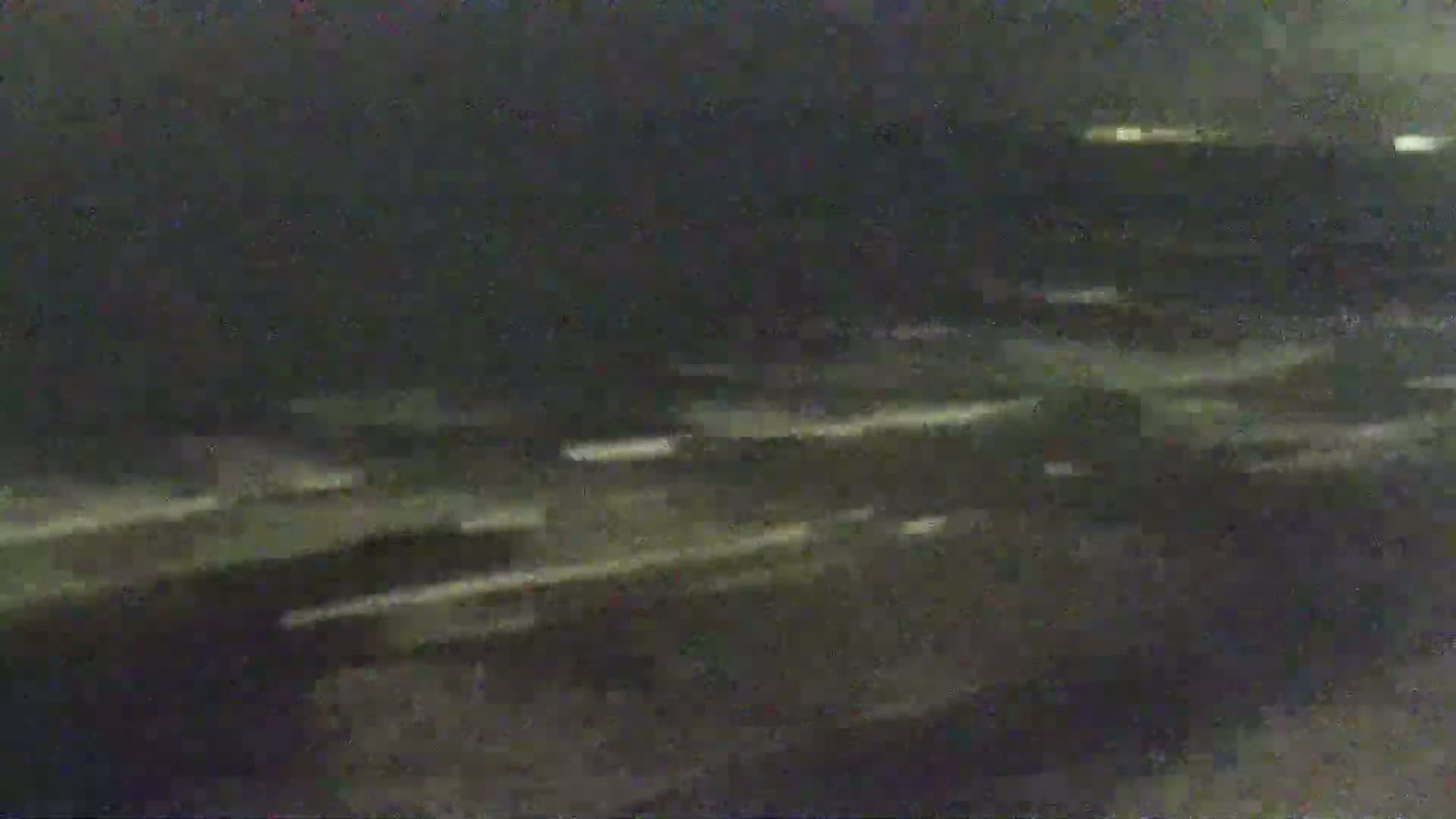 A blurry nighttime image shows streaks of light suggesting fast-moving vehicles on a dark roadway.