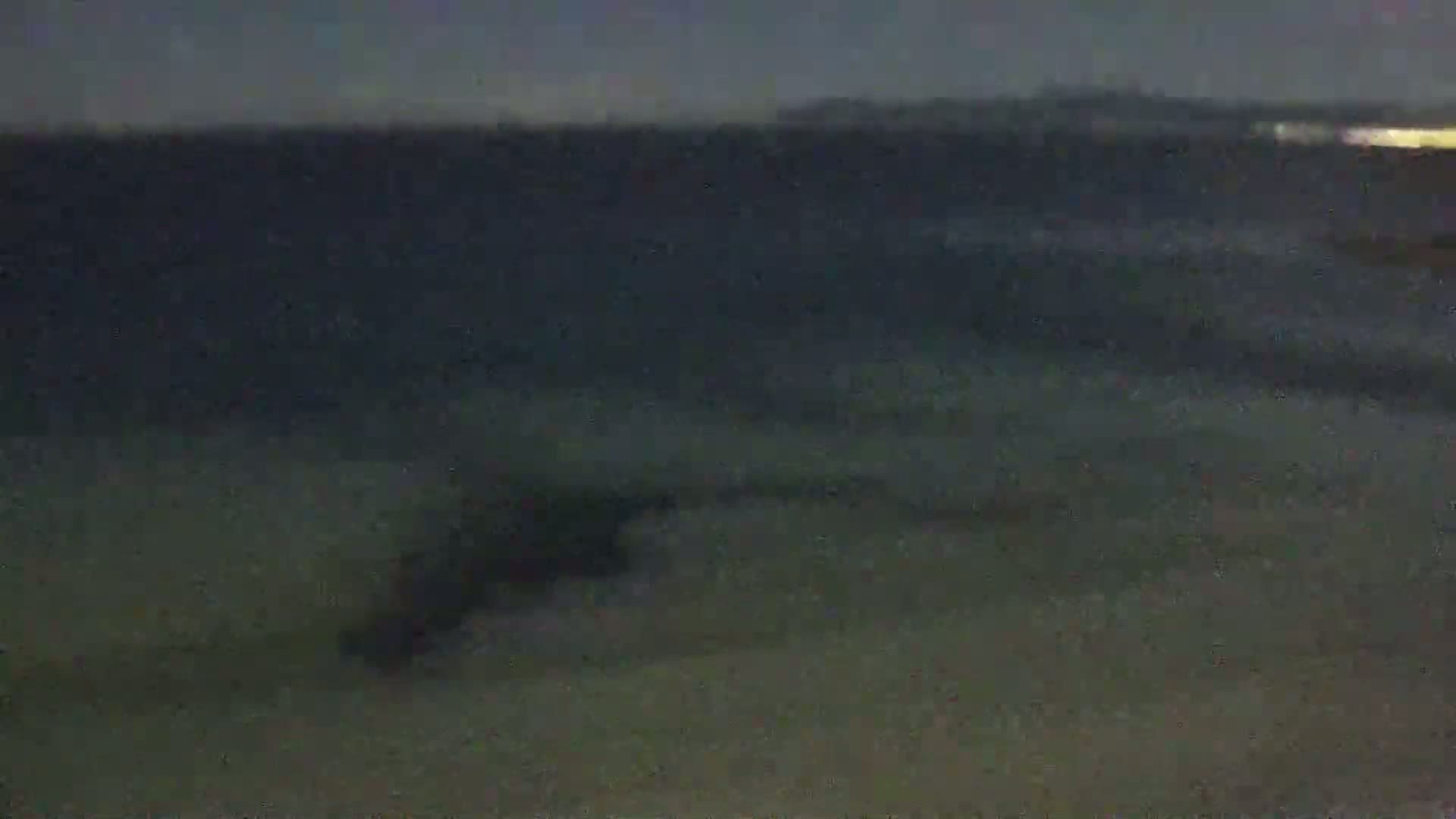 A dark, blurry image shows a body of water at night with subtle wave patterns.