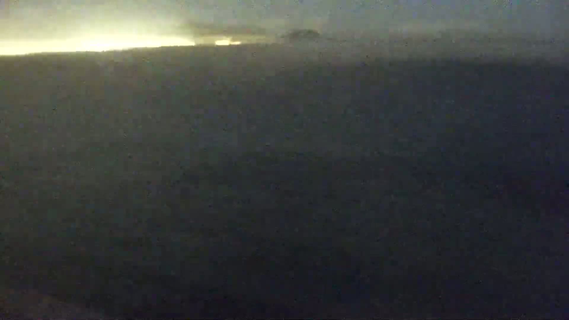 A dark, hazy landscape is visible at twilight or dawn, with a bright horizon line.