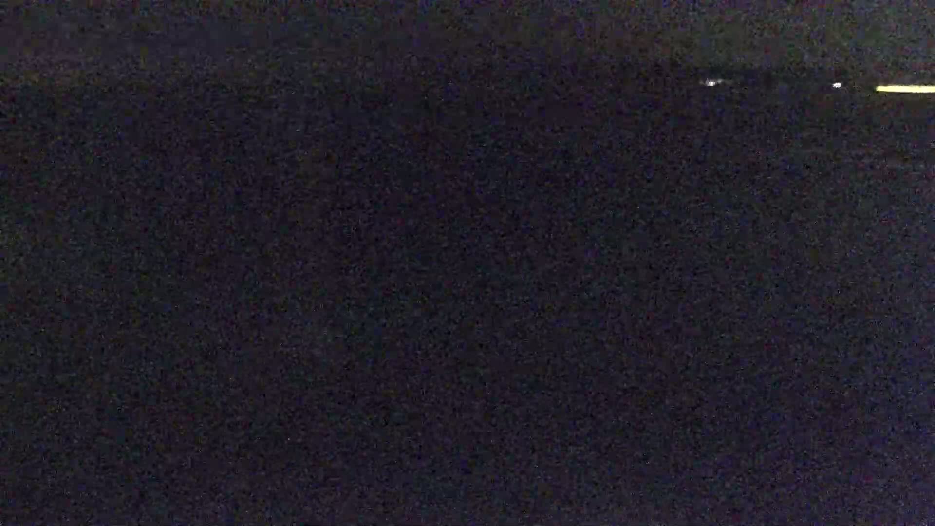 A dark, possibly nighttime scene shows a few distant lights on the horizon.