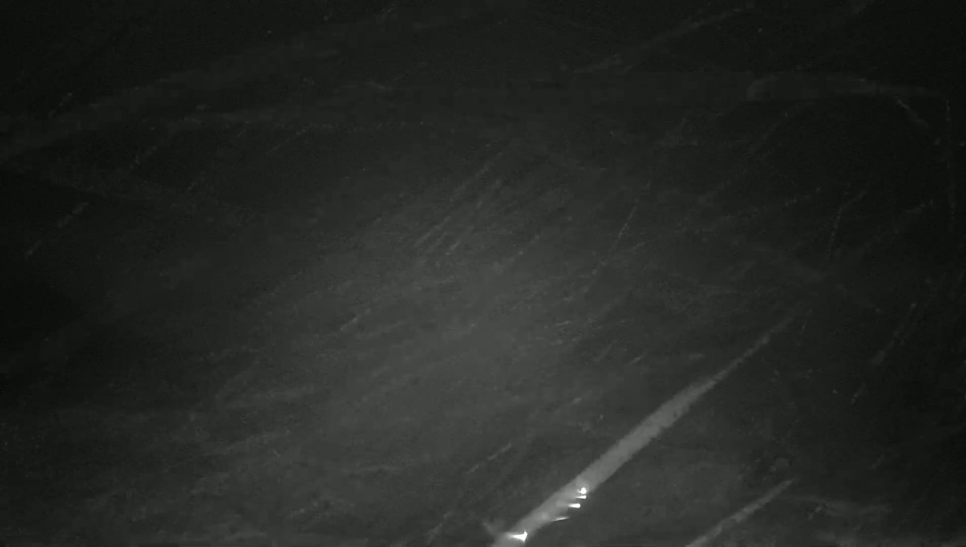 A dark, possibly nighttime, image shows two streaks of light in the lower right corner against a textured, dark gray background.