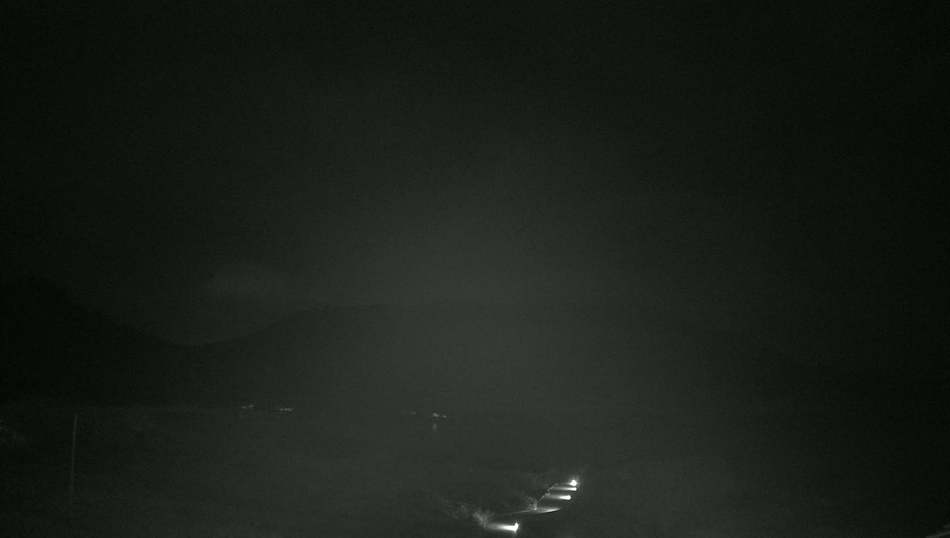 A nighttime, hazy view shows a dark road with a few sets of headlights visible in the distance.