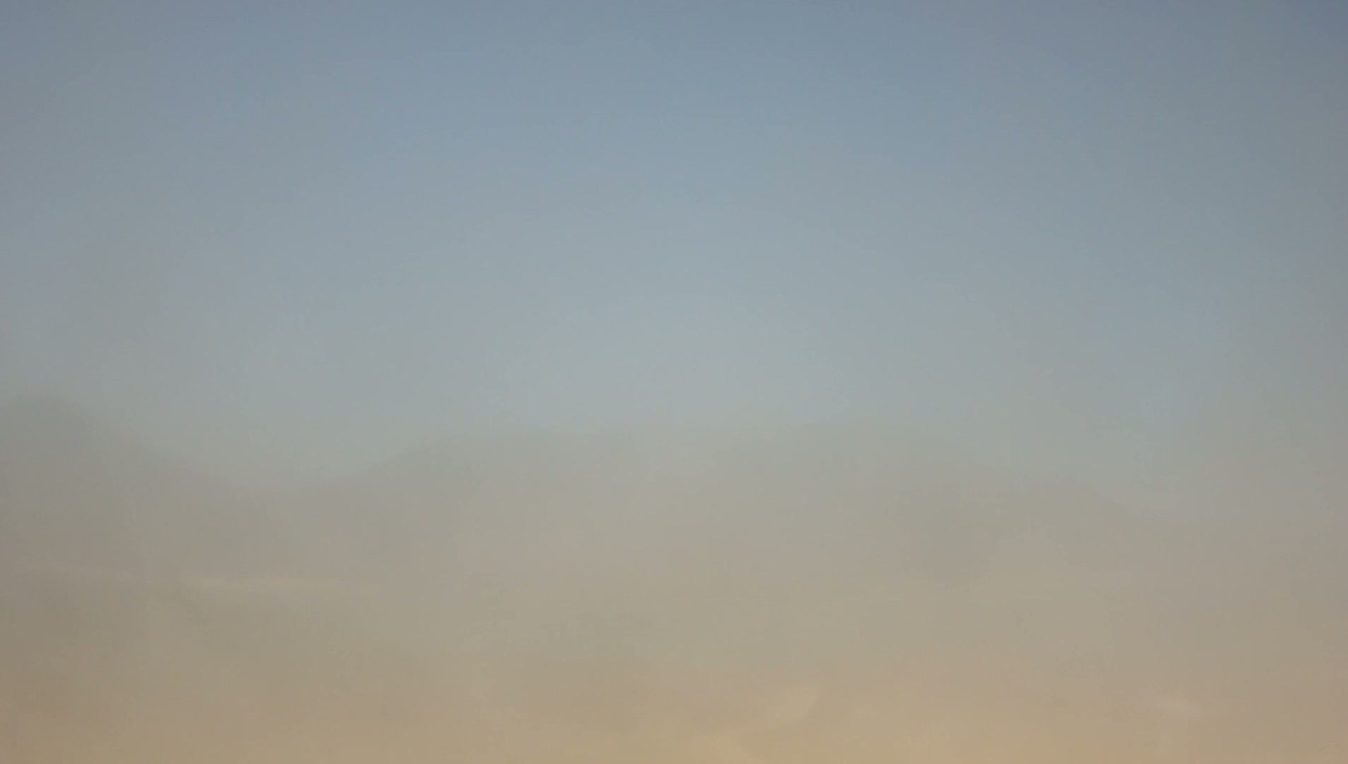 A hazy, muted sky blends from light blue at the top to a warmer beige at the bottom.