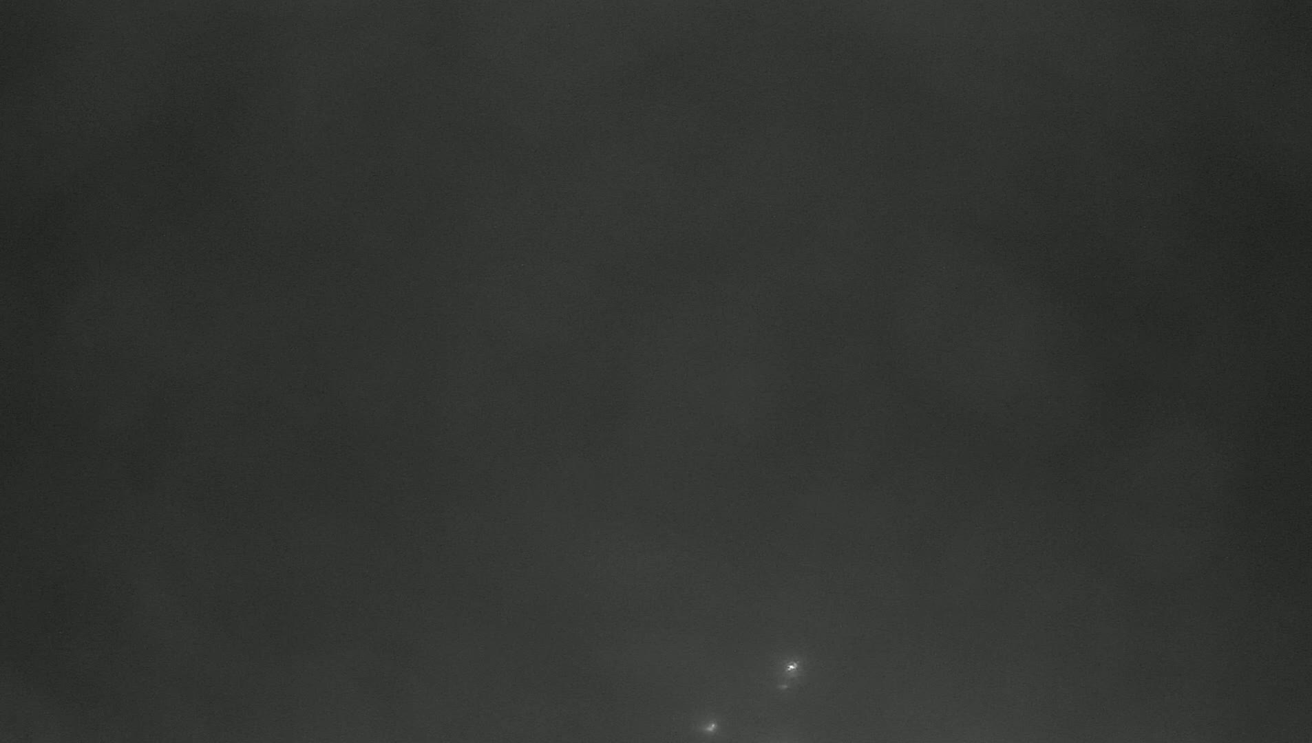 A dark, overcast sky with two faint lights visible near the bottom.