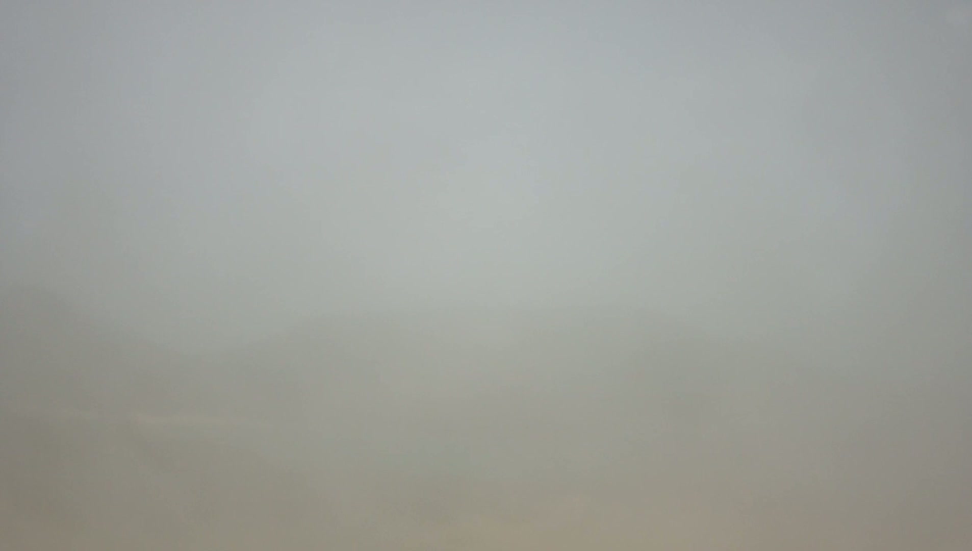 A blurry, gray landscape is obscured by heavy fog.