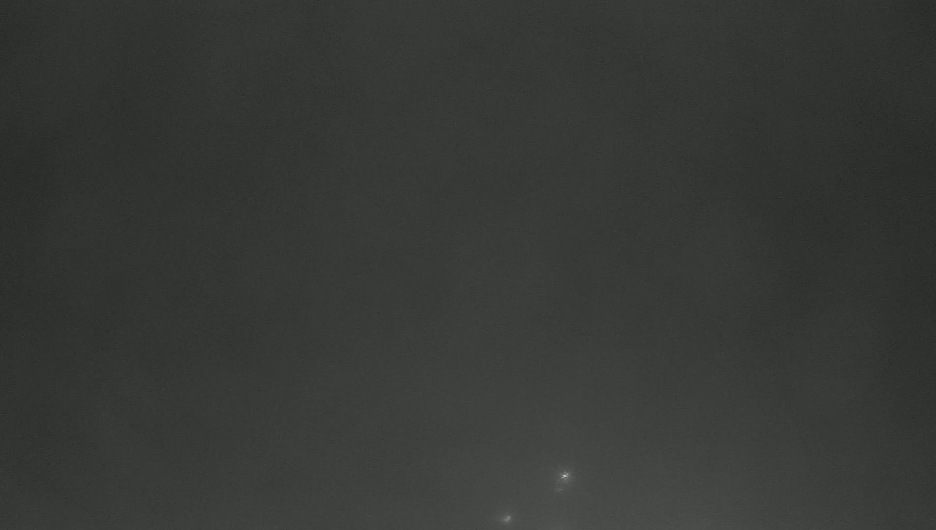 A dark gray, possibly nighttime sky shows two faint, bright lights near the bottom.