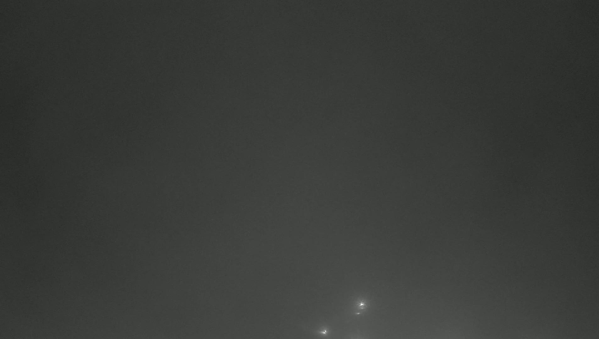 A dark, hazy sky with a few faint lights visible near the bottom.