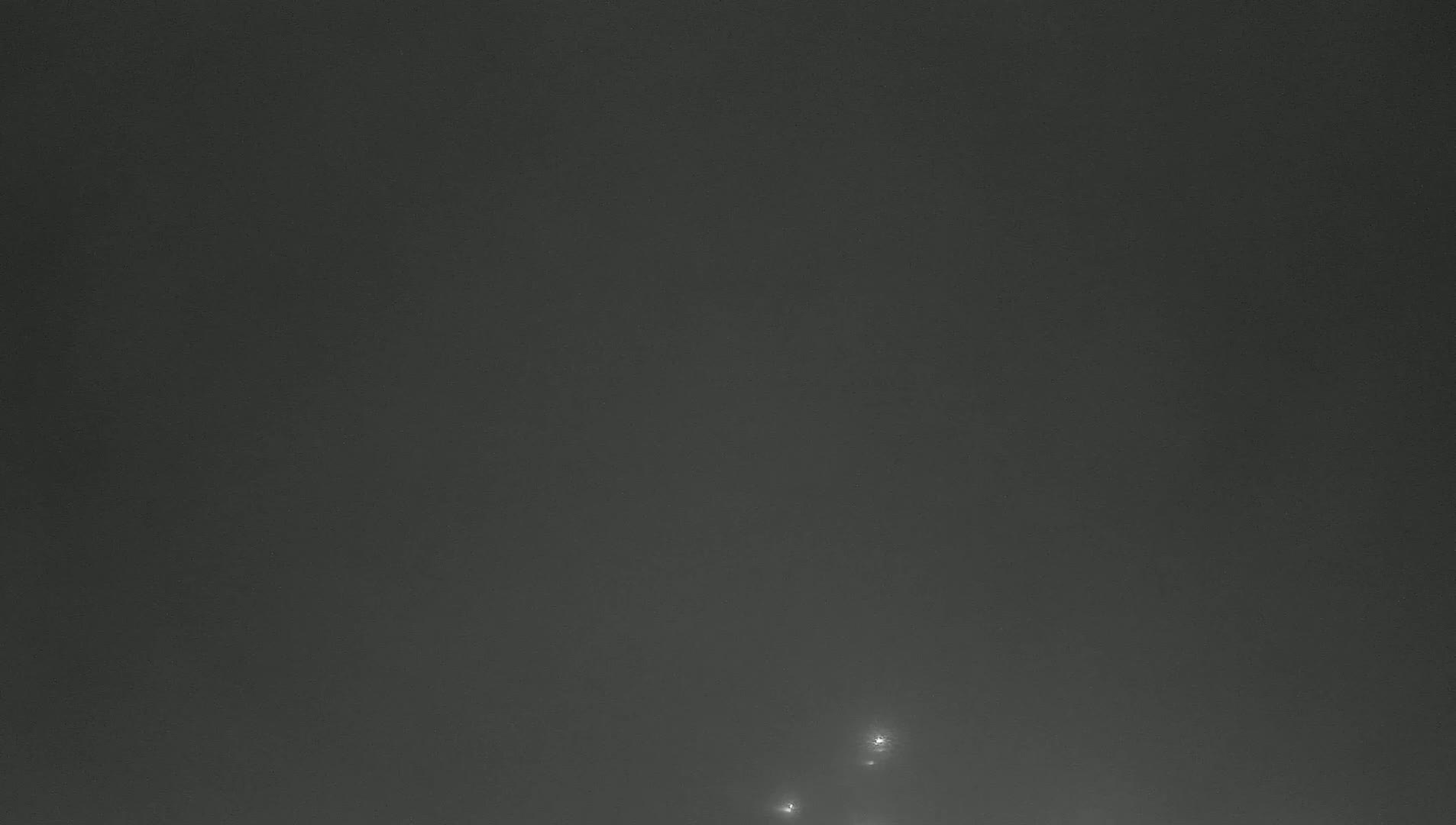 A dark, foggy sky with three faint lights visible in the lower portion.