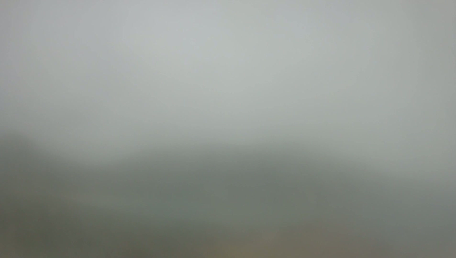A blurry, hazy landscape is barely visible through a thick fog.