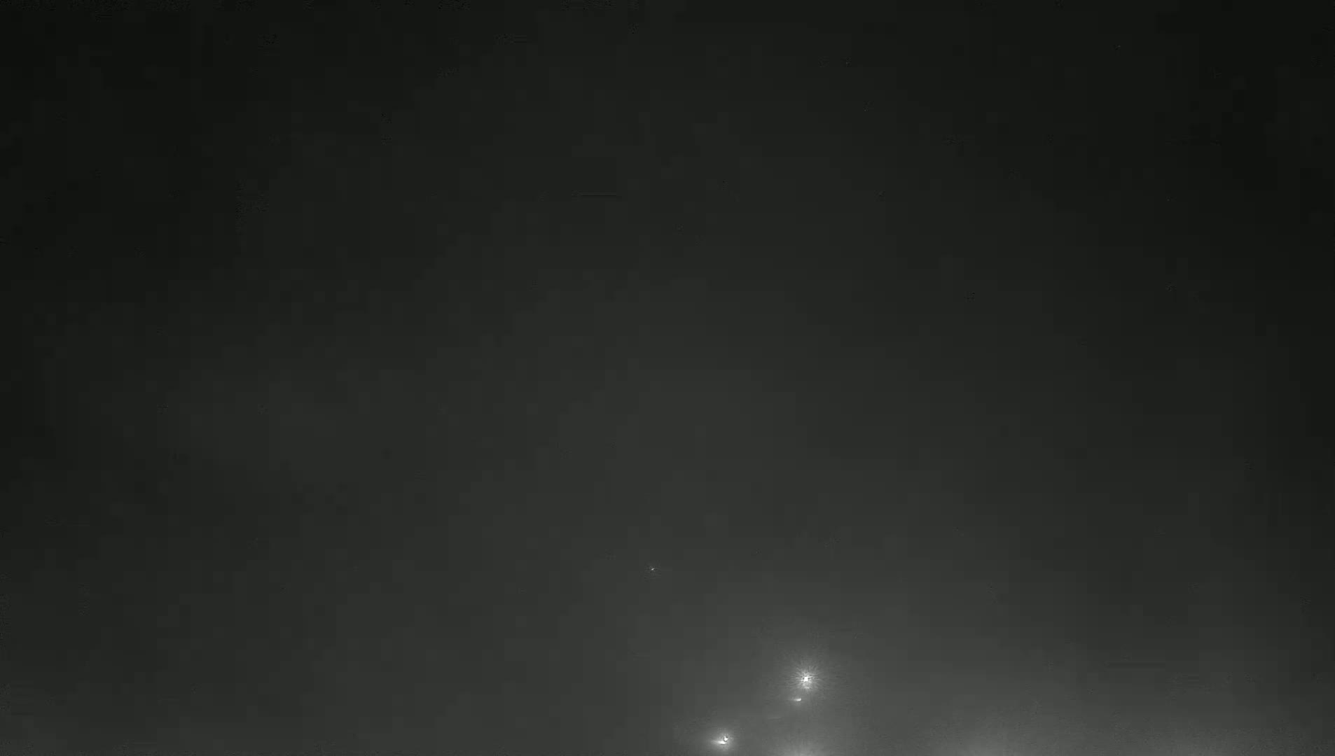 A dark, foggy night scene shows distant lights faintly visible through the haze.