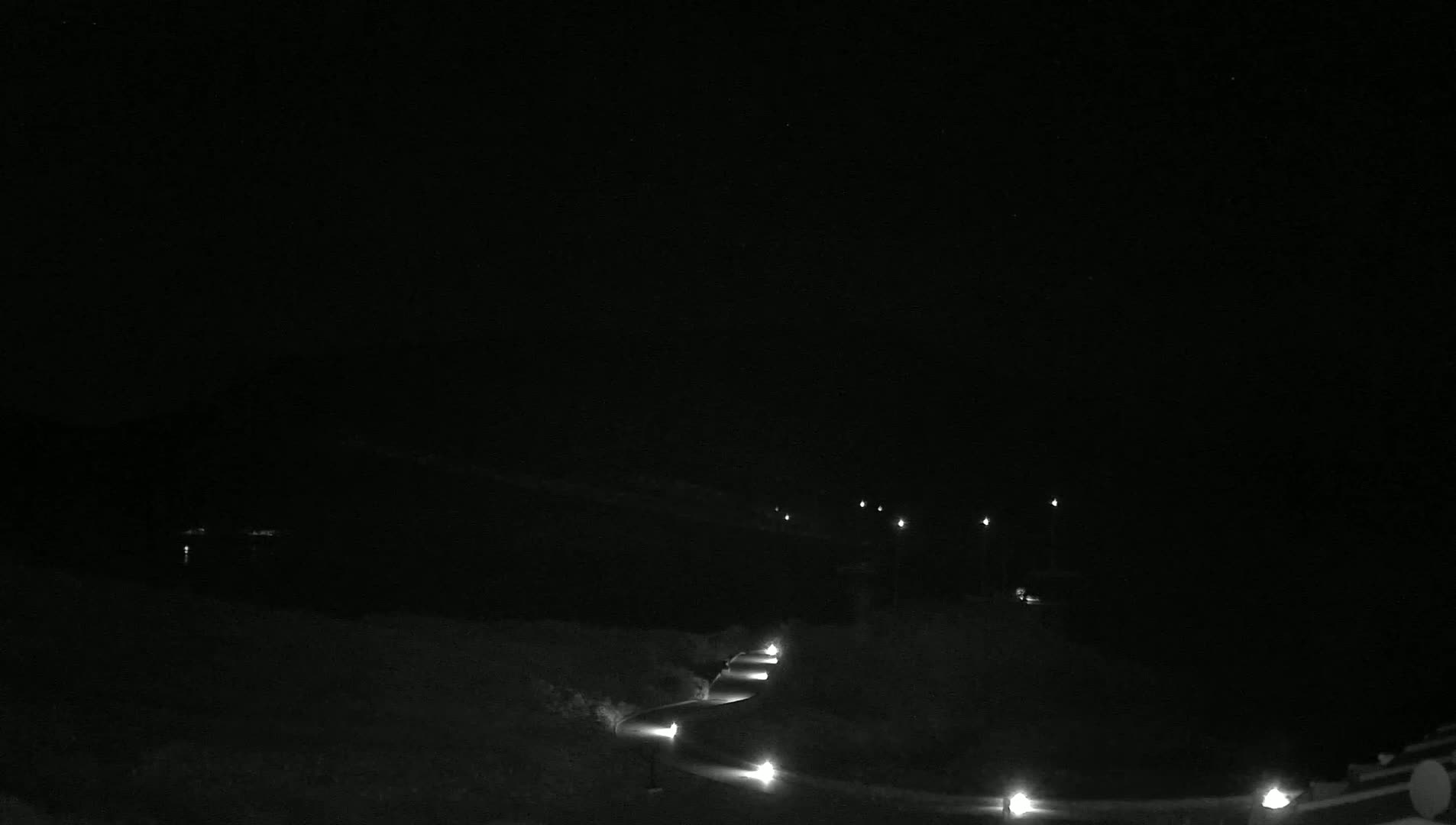 A winding road with dimly lit lights is visible at night.