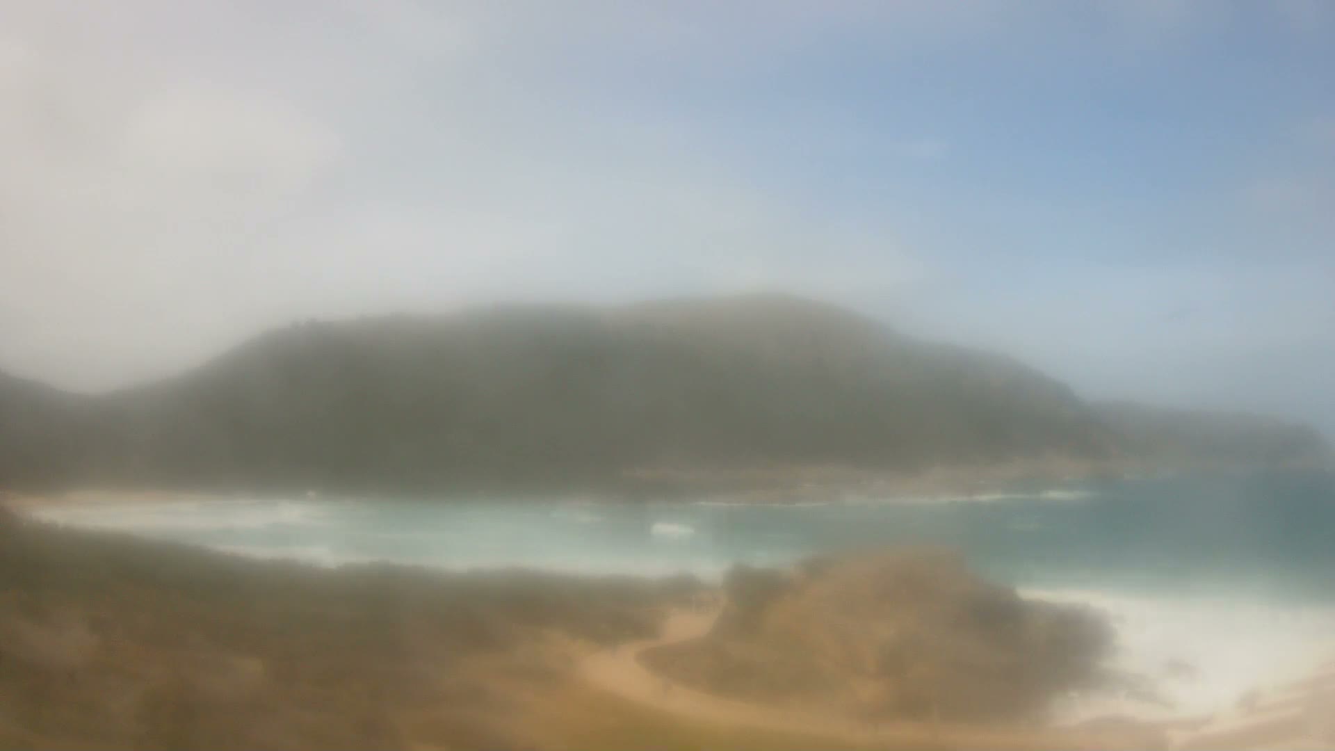 A very hazy outdoor landscape features a pale, indistinct sky blending into a slightly darker, brownish-grey ground, with extremely poor visibility.