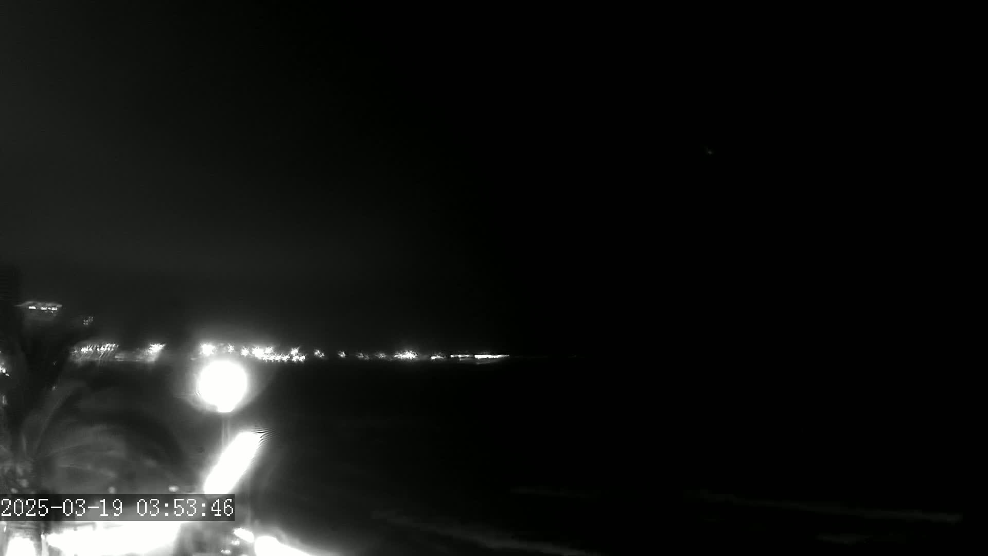 A nighttime, low-light image shows a blurry view of lights in the distance, possibly from a roadway or buildings.