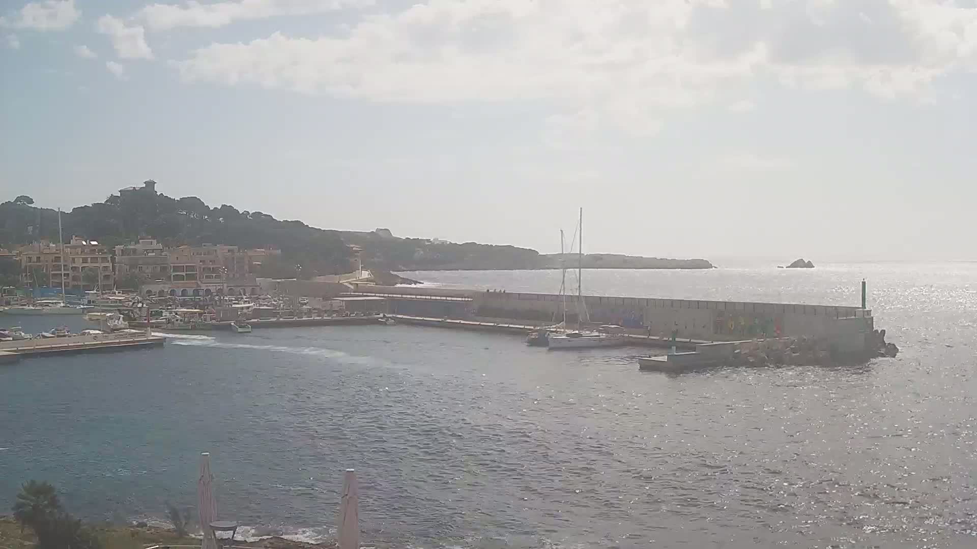 A harbor filled with boats is situated next to a town on a partly sunny day.