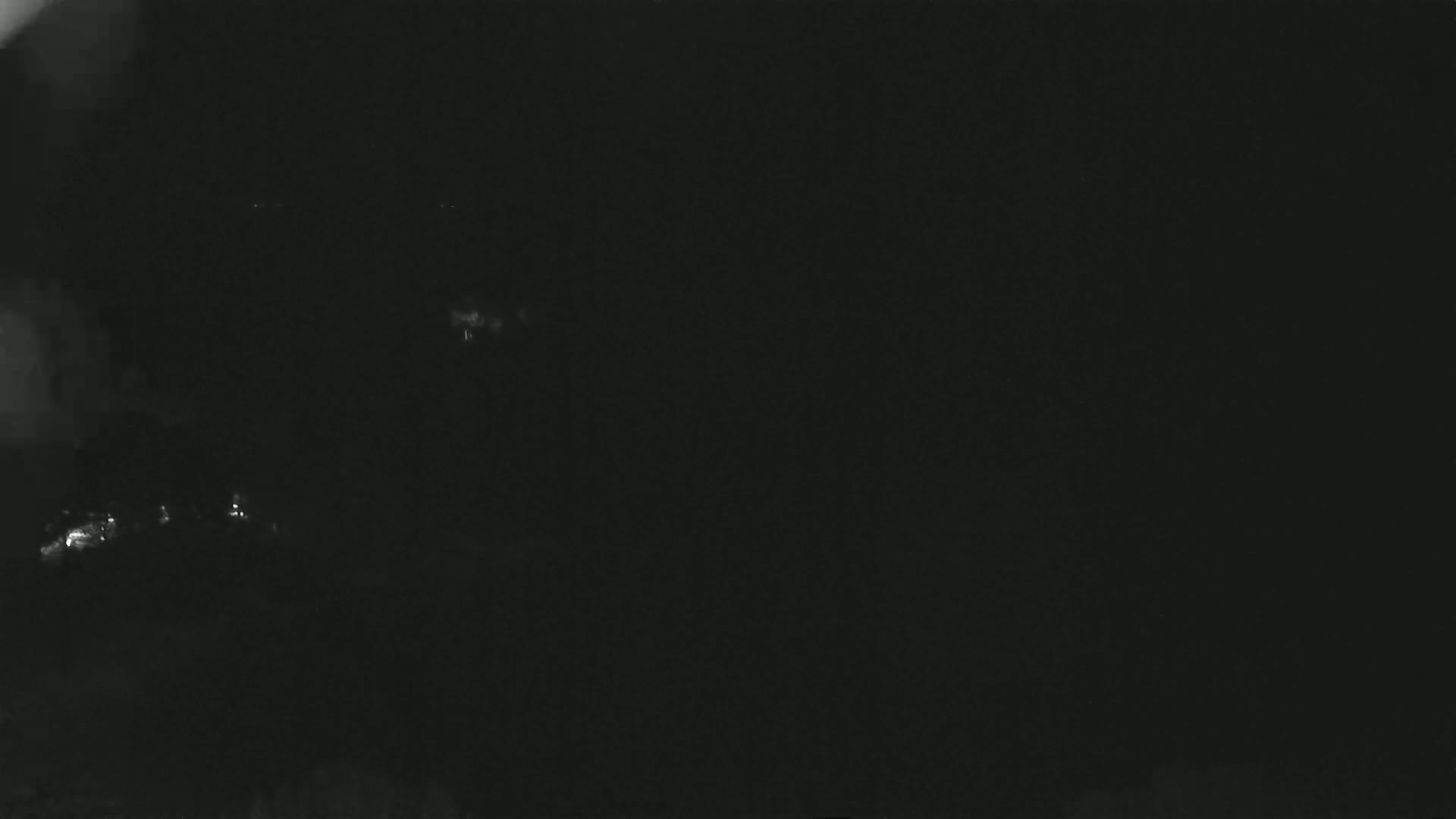 A dark, nighttime image shows a few faint lights in the distance.