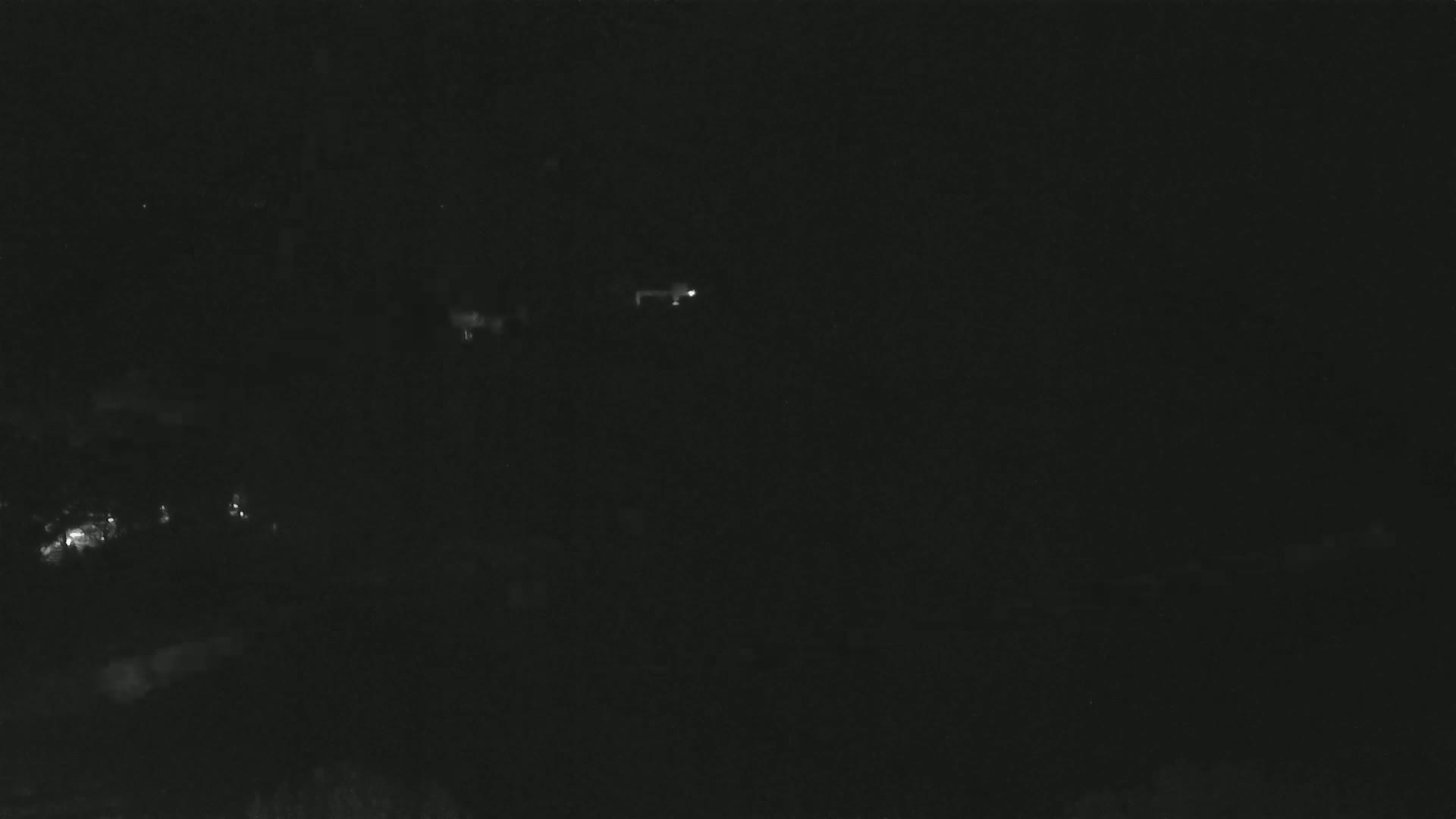 A dark, nighttime scene shows a few faint lights in the distance.