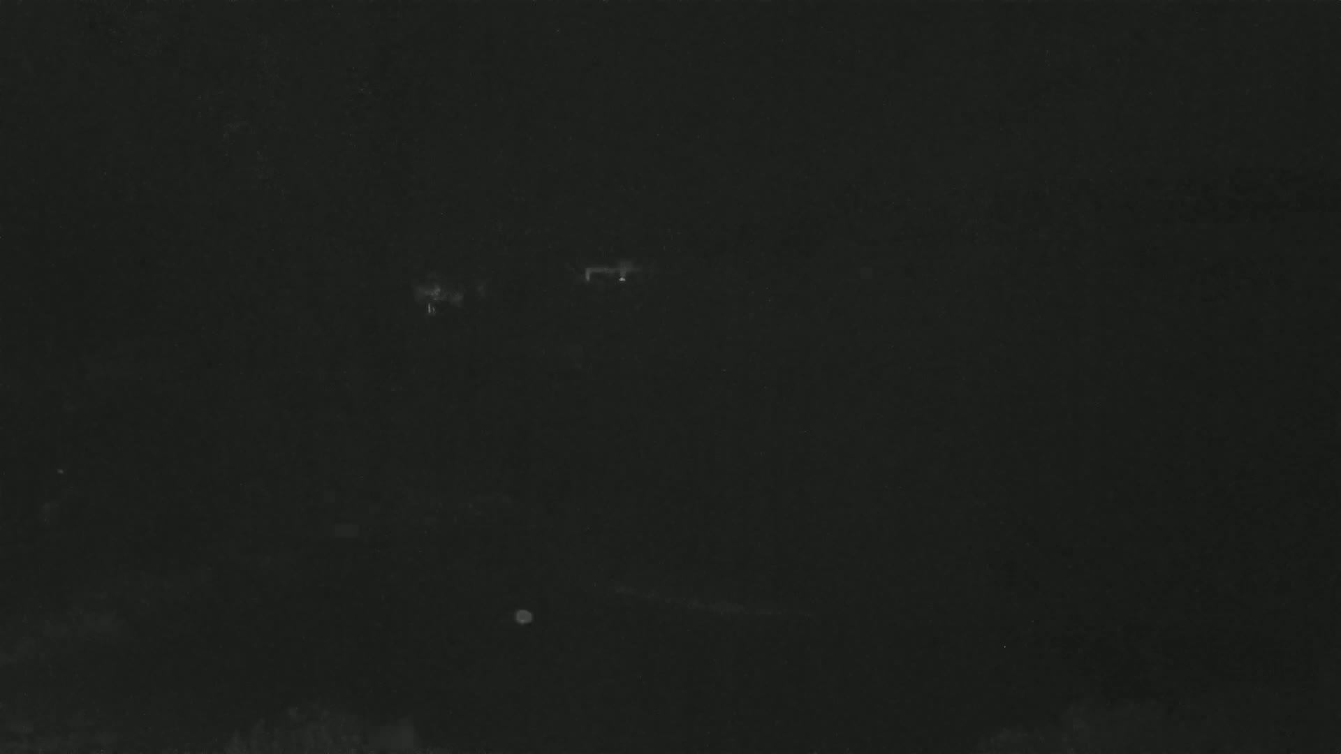 A very dark image shows faint, indistinct light sources in the distance at night.