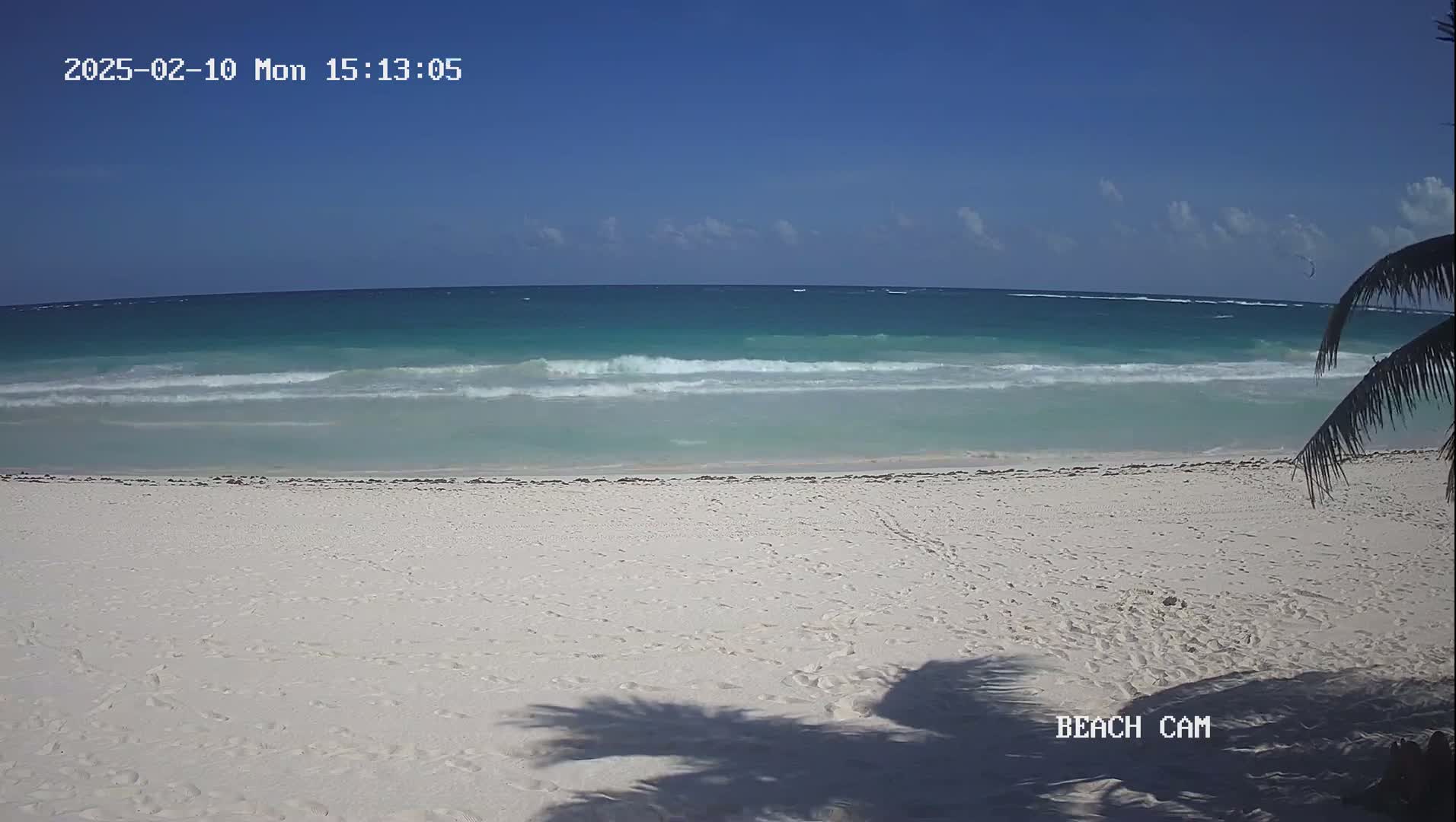A white sandy beach with small waves rolling onto the shore on a sunny day.