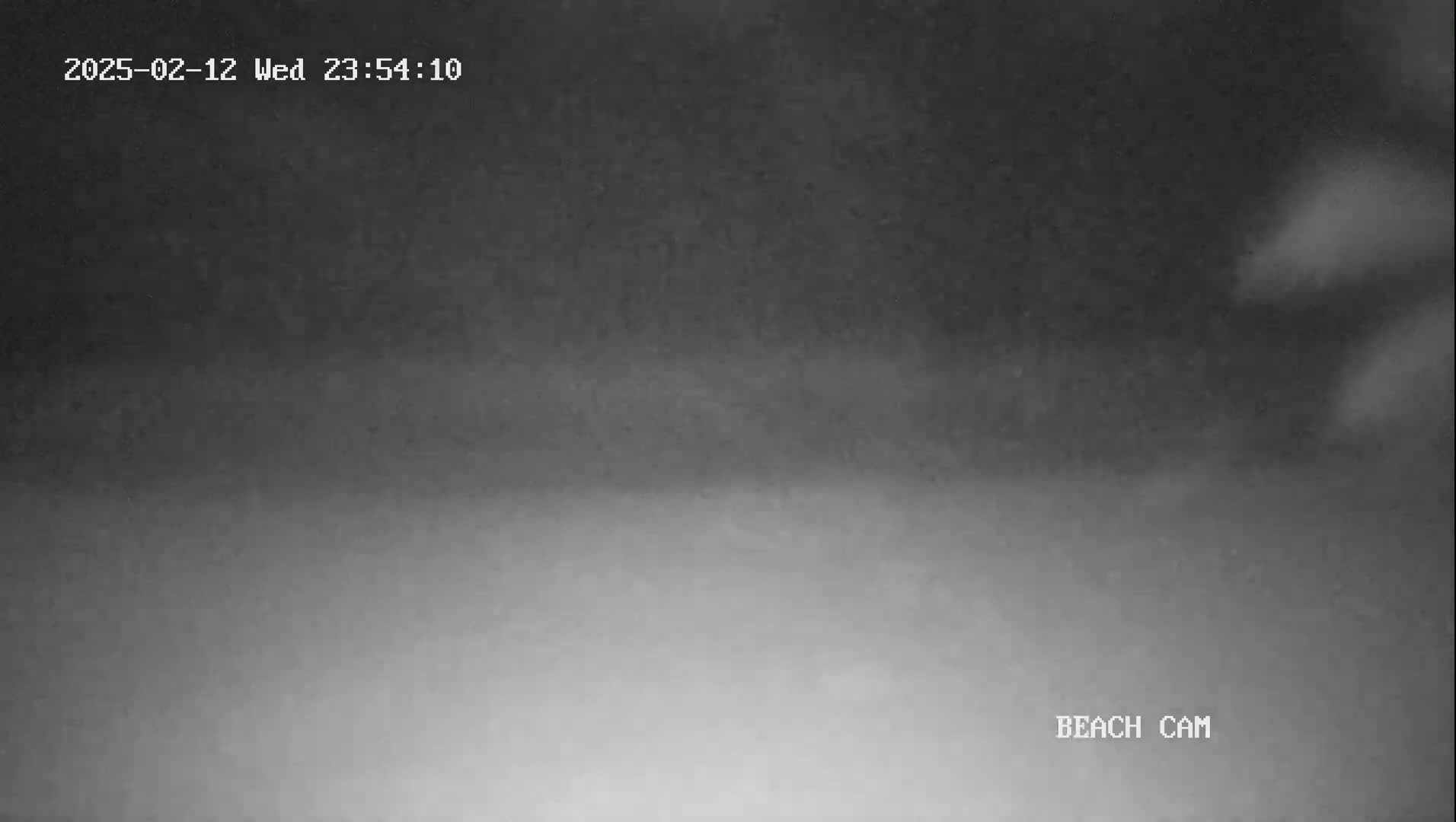 A nighttime, low-light beach scene is shown with dark, hazy conditions.