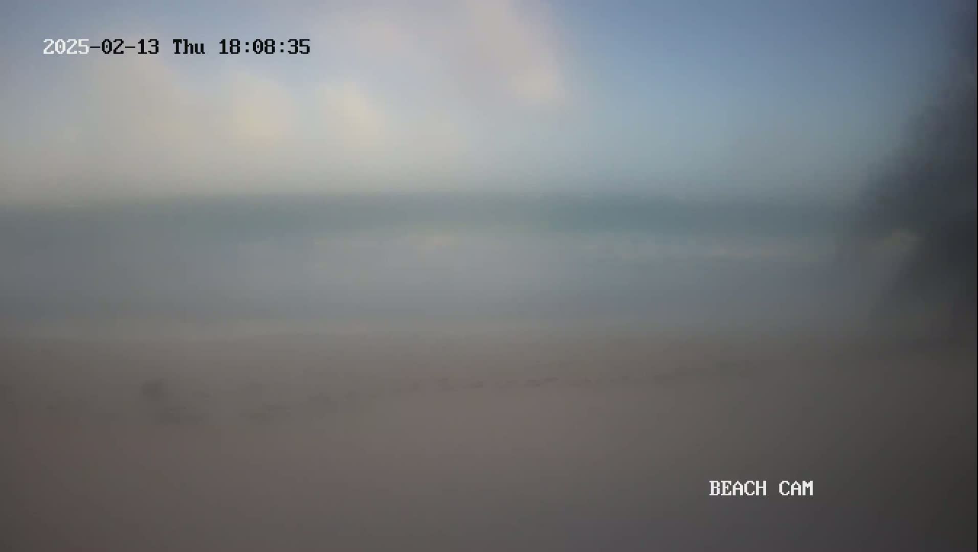 A hazy, overcast sky hangs over a mostly obscured beach scene.