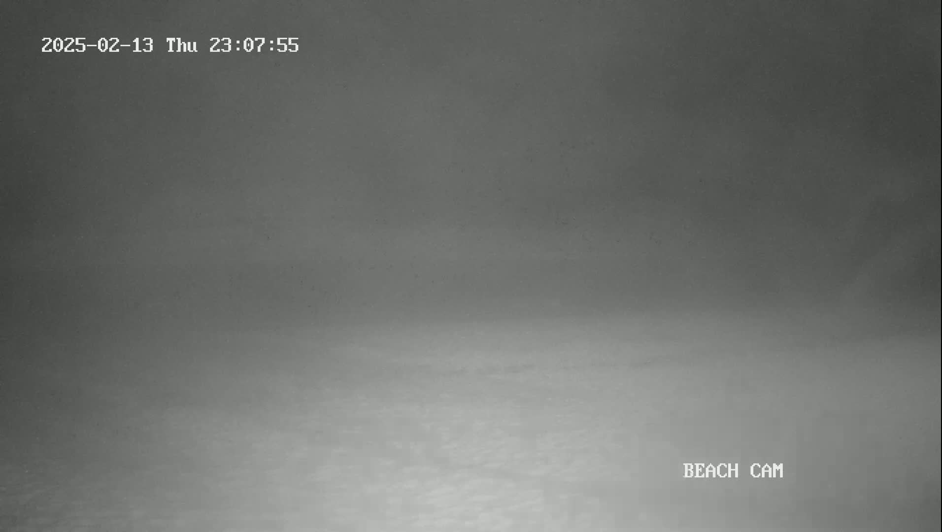 A low-visibility, nighttime shot shows a gray, seemingly flat expanse of water or land under a foggy sky.