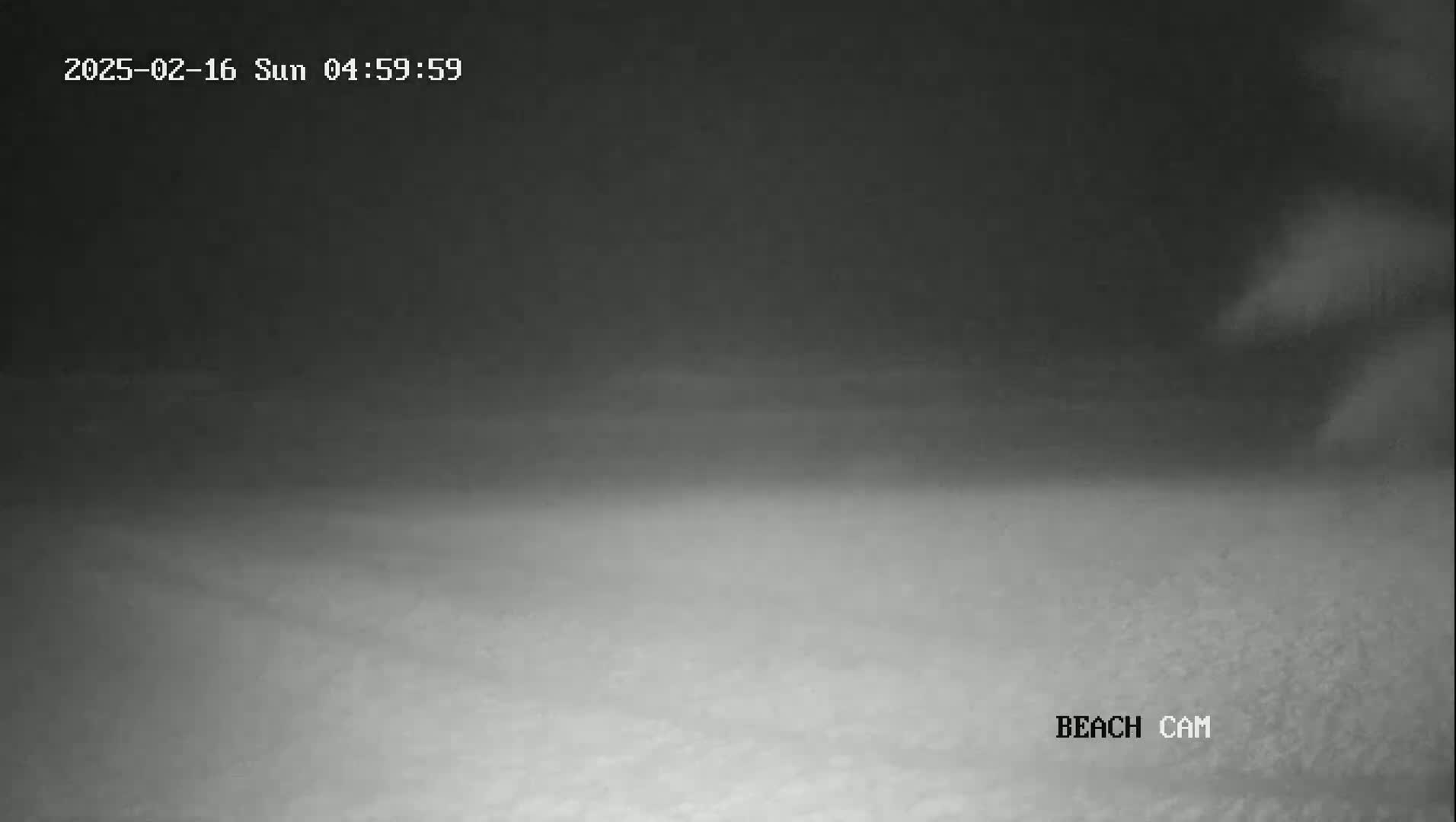 A dark, blurry image shows a beach at night under foggy or hazy conditions.