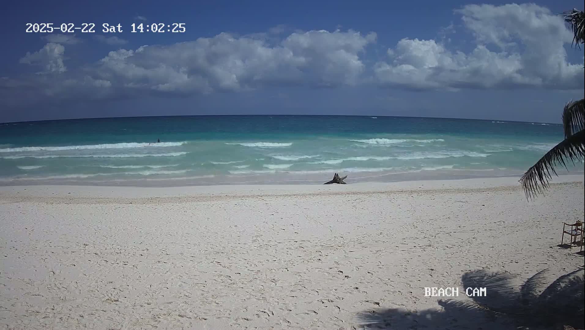 A white sandy beach with gentle waves on a partly cloudy day.