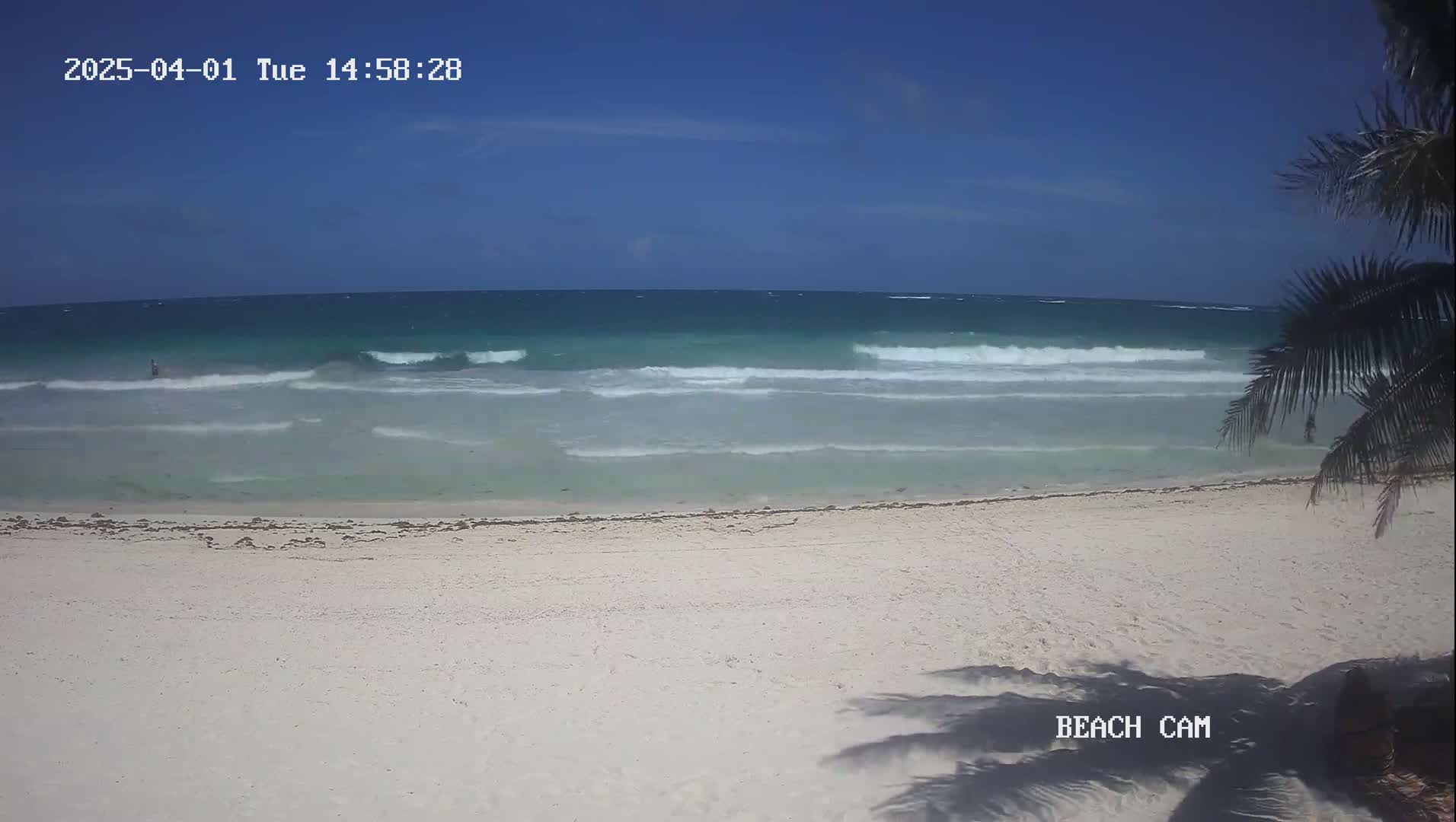 A white sandy beach with gentle waves under a clear blue sky.