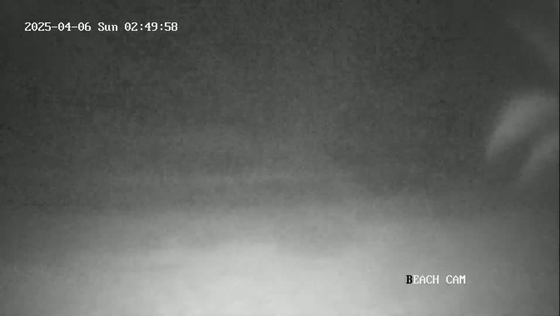 A nighttime beach scene is shown with hazy or foggy conditions.