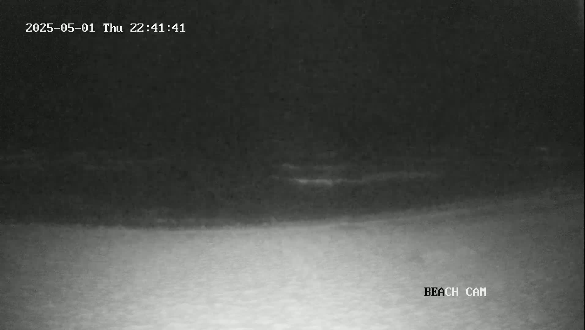 A nighttime beach scene shows a dark sky and lighter-colored sand under it.