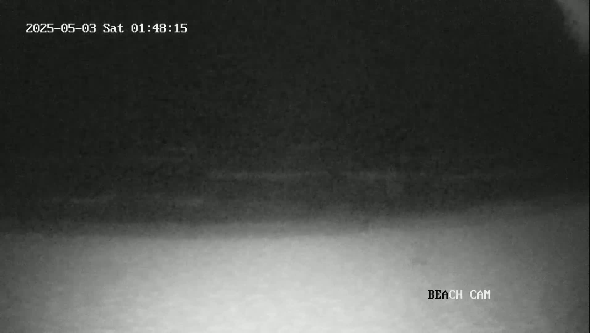 A dark, nighttime beach scene is visible with a lighter gray area at the bottom, suggesting sand or water.