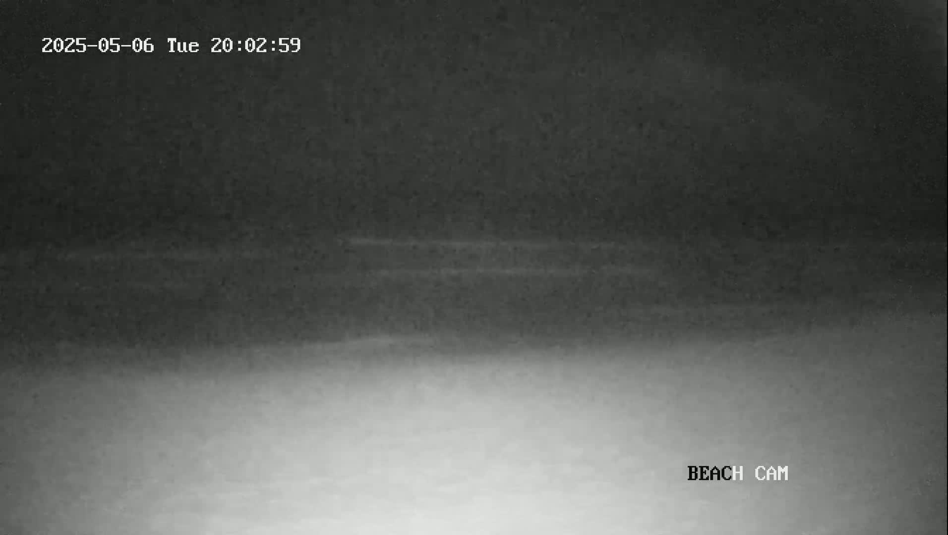 A nighttime beach scene is shown with a dark, hazy sky and a lighter gray area near the bottom, likely representing the sand.