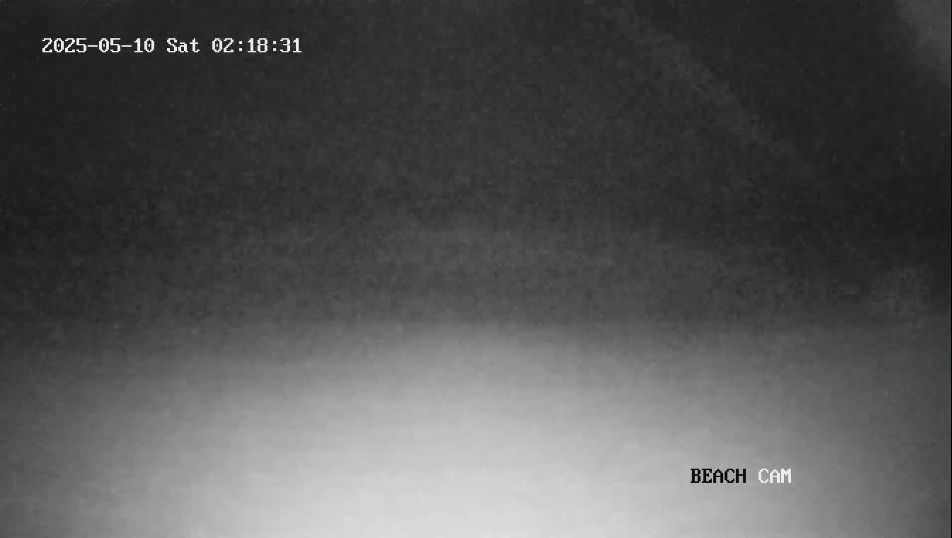 A low-light, grainy image shows a dark sky gradually lightening towards a bright horizon.