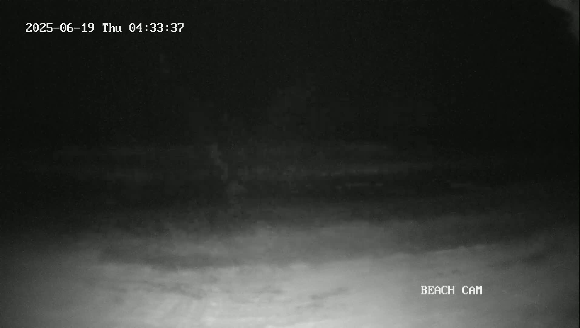 A nighttime beach scene is shown with dark, hazy conditions obscuring most details.