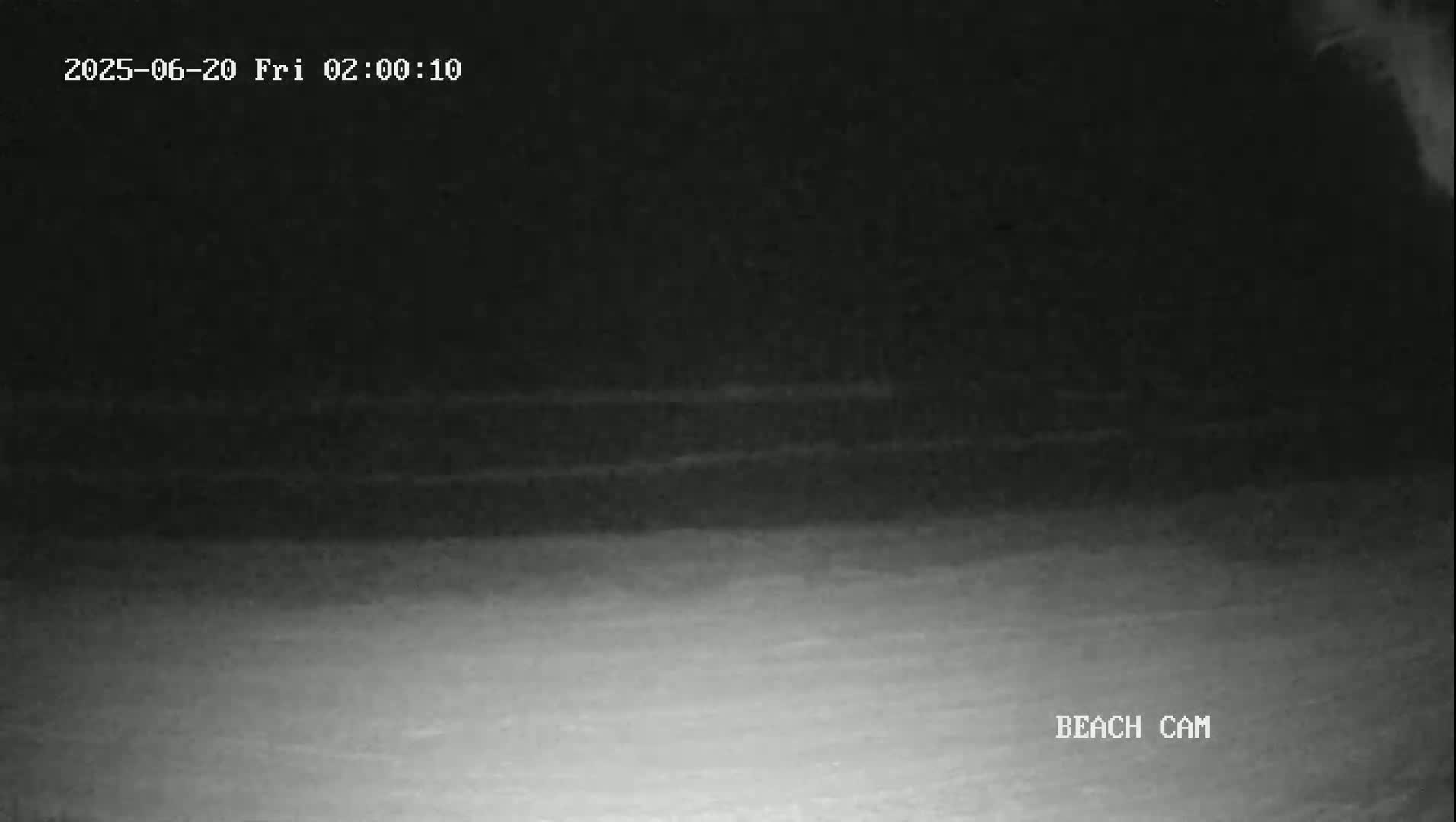 A nighttime beach scene shows dark water under a dark sky.
