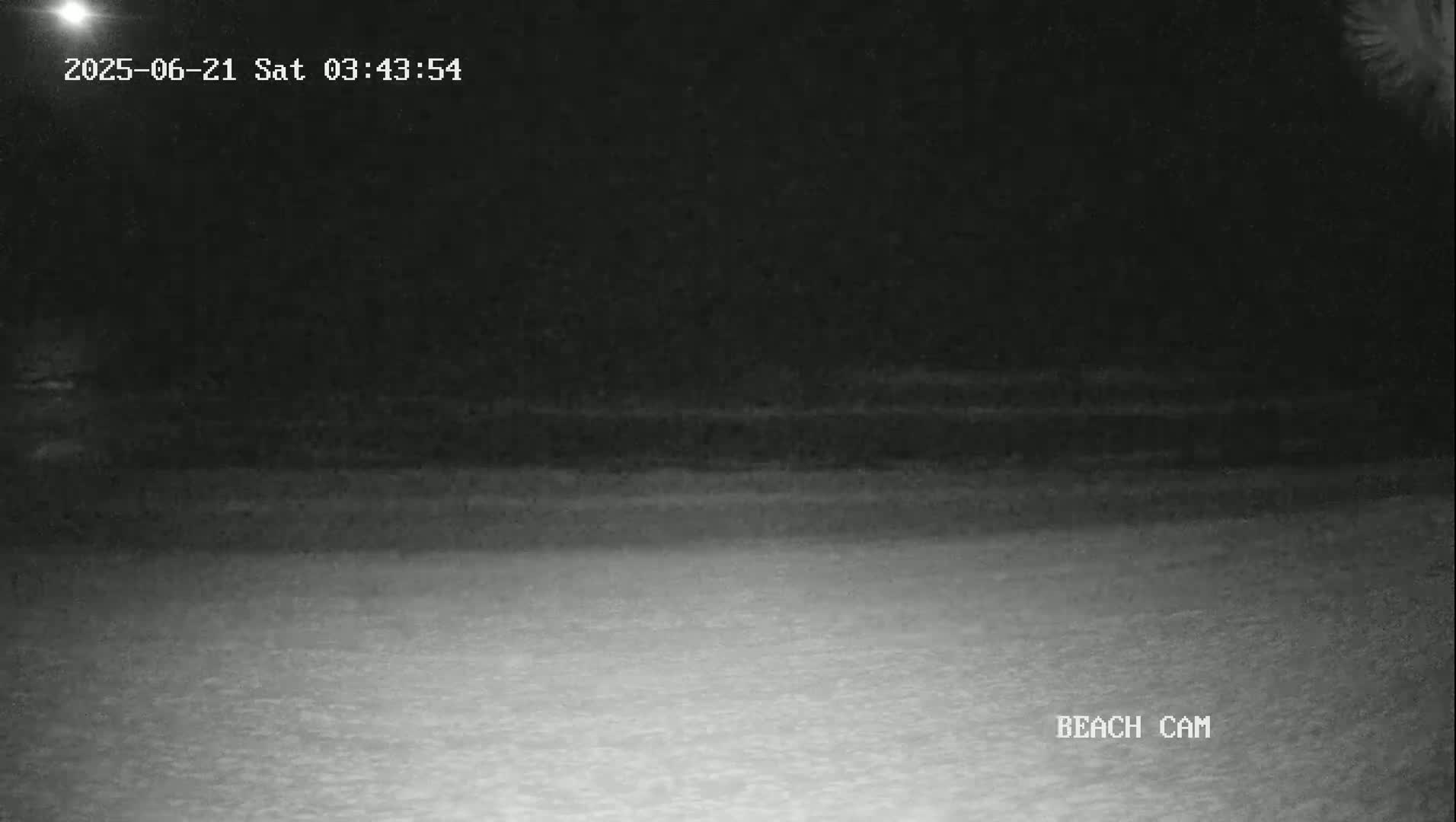 A dark, nighttime beach scene is shown with a flat, mostly calm ocean.
