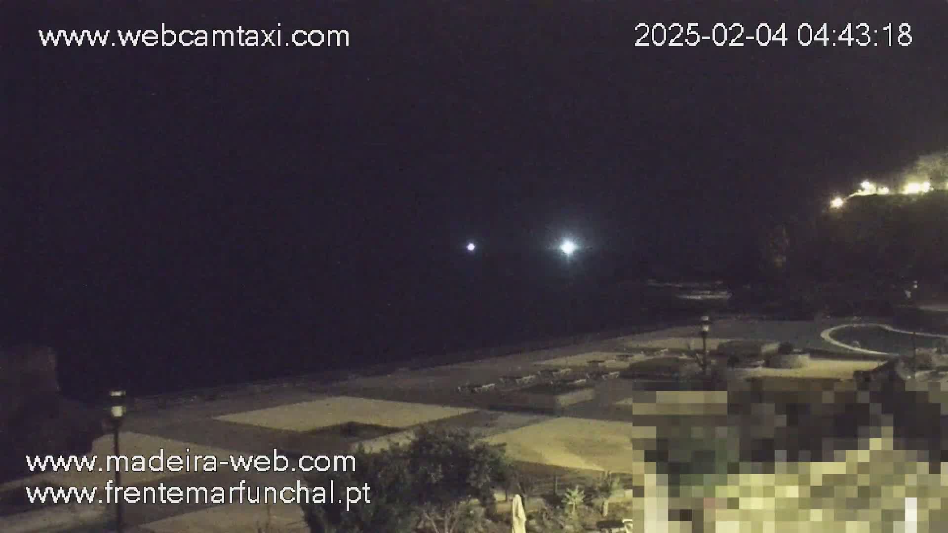 A nighttime view of a dark beach and coastline with two bright lights visible in the sky.