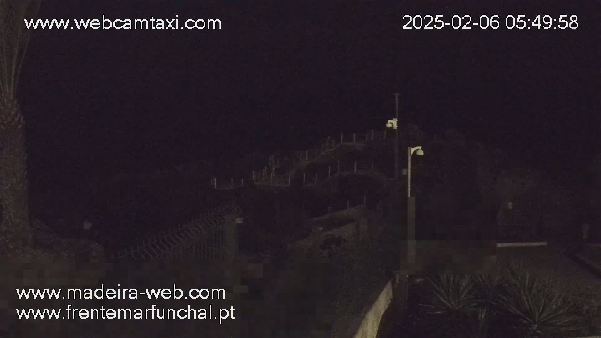 A nighttime, dark view of a structure partially obscured by shadows, with some vegetation visible in the foreground.