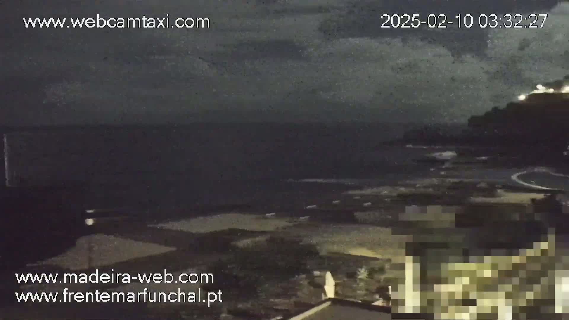 A nighttime coastal scene shows a dark ocean under a cloudy sky.