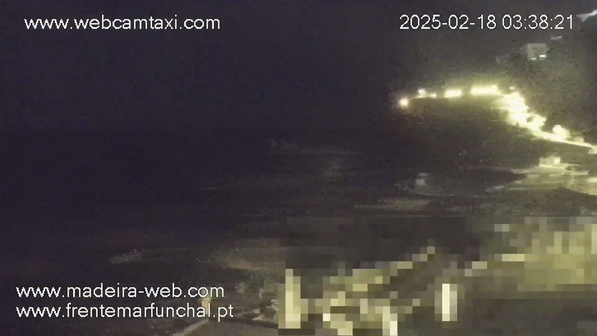 A nighttime, low-light image shows a brightly lit vessel moving across dark water with some wave action visible.