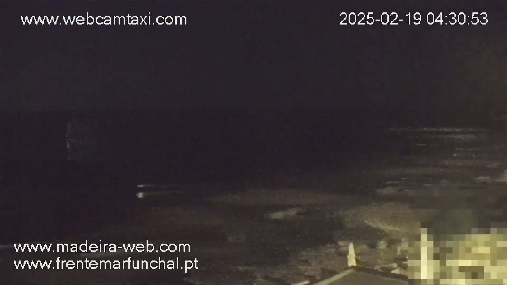 A nighttime coastal scene shows dark, wavy water under a dark sky.