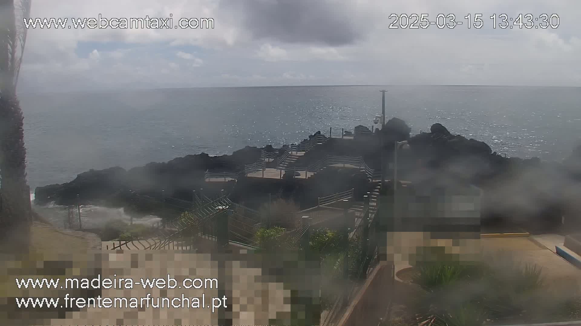 A misty, overcast day reveals a rocky coastal area with stairs leading down to the ocean, partially obscured by mist.