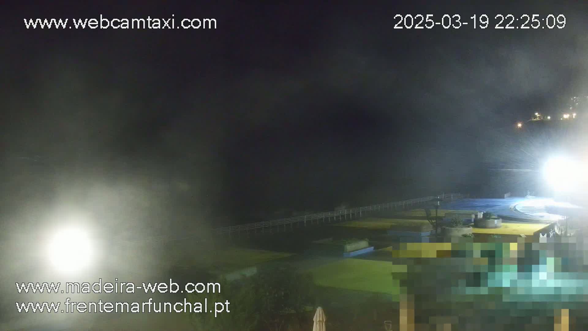 A nighttime, foggy view of a waterfront area with lights illuminating a pier and buildings.