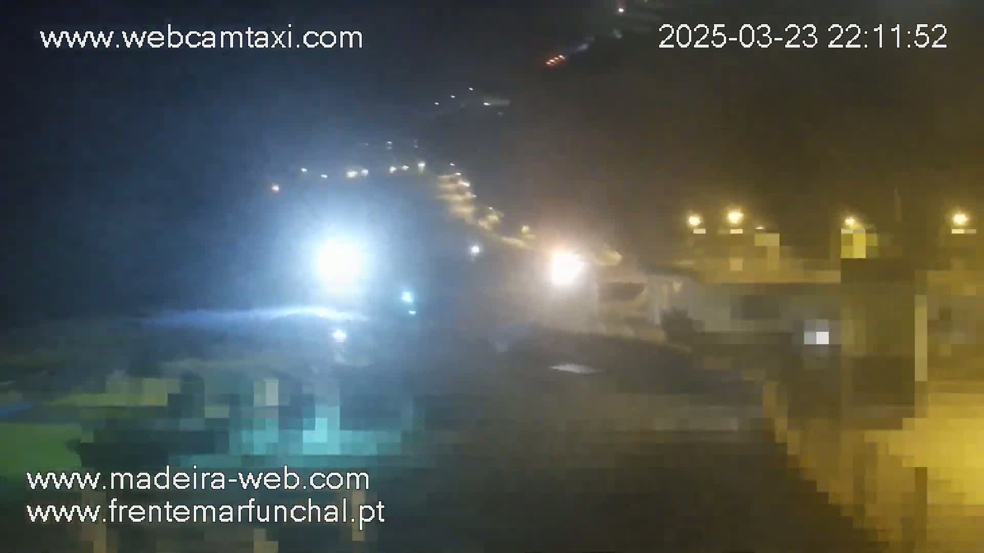 A hazy night scene shows a road with blurry lights from vehicles and buildings.