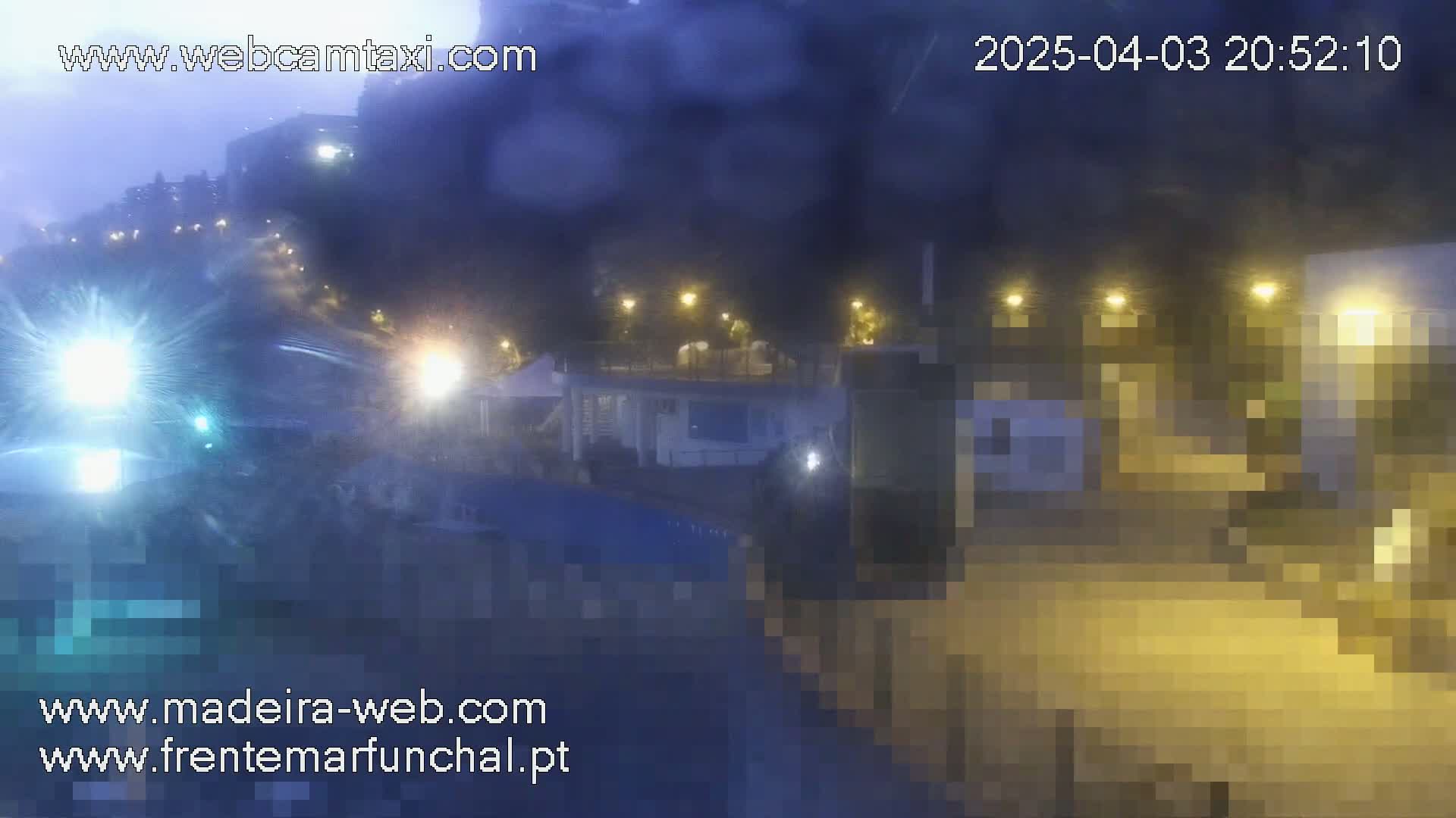 A hazy, nighttime view of a street scene with illuminated buildings and vehicles.