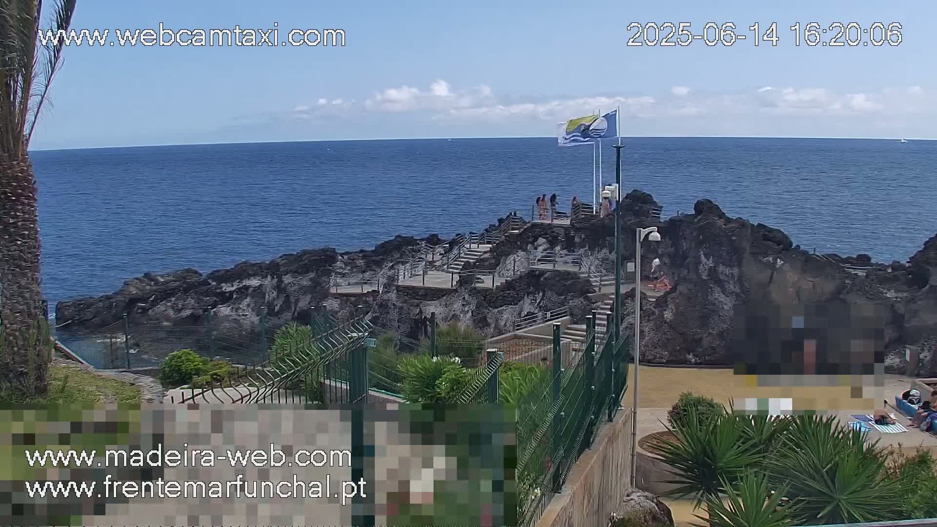A rocky oceanside area with steps leading down to a small, enclosed pool, under a partly cloudy sky.